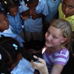 Teenagers praying for local children on mission trip